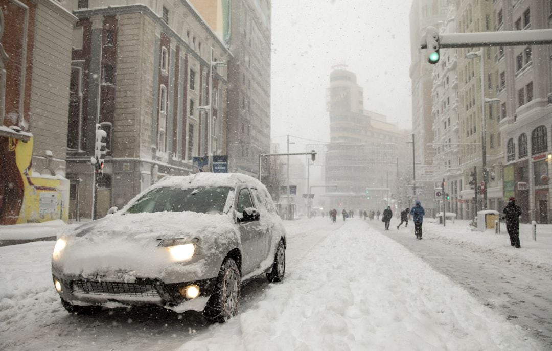 Un coche conduce bajo la nieve en Madrid.