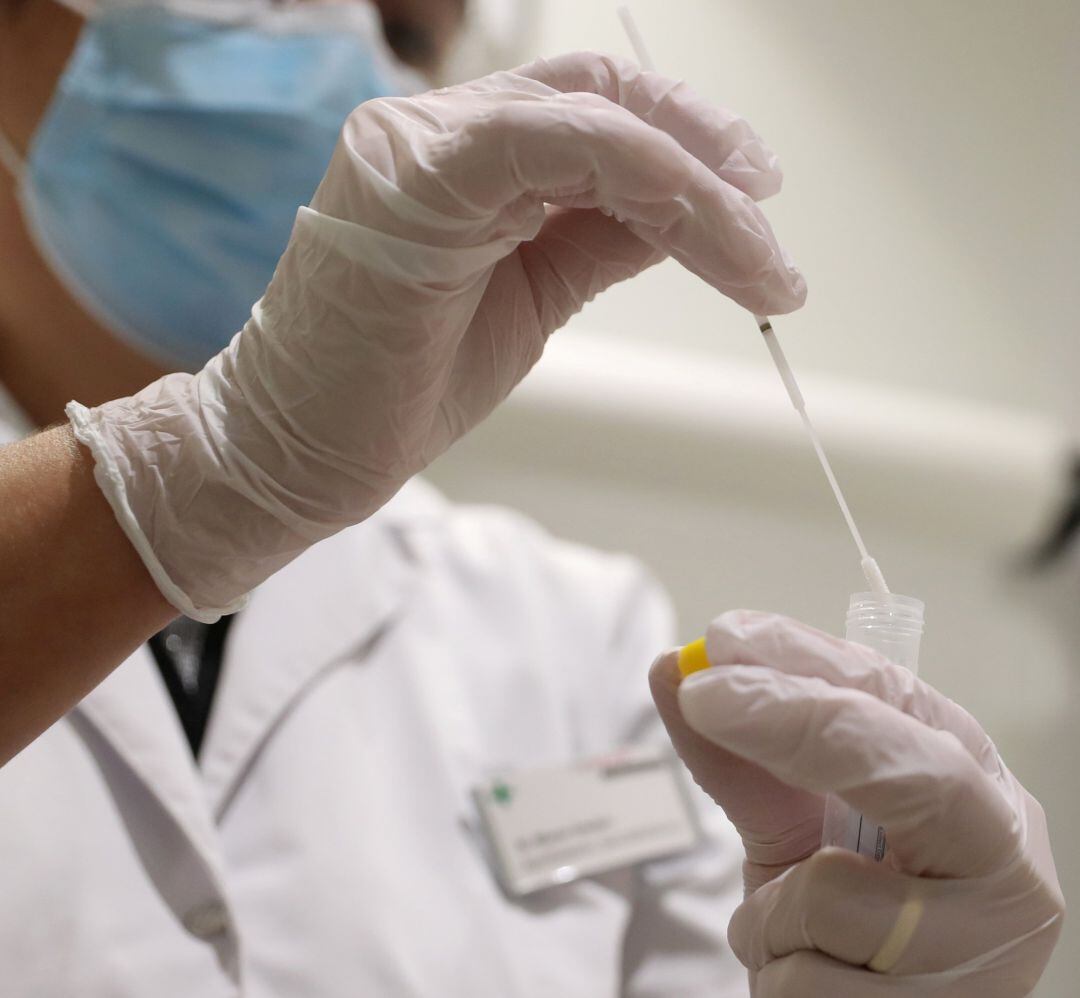 Personal sanitario con una muestra de PCR en sus manos.