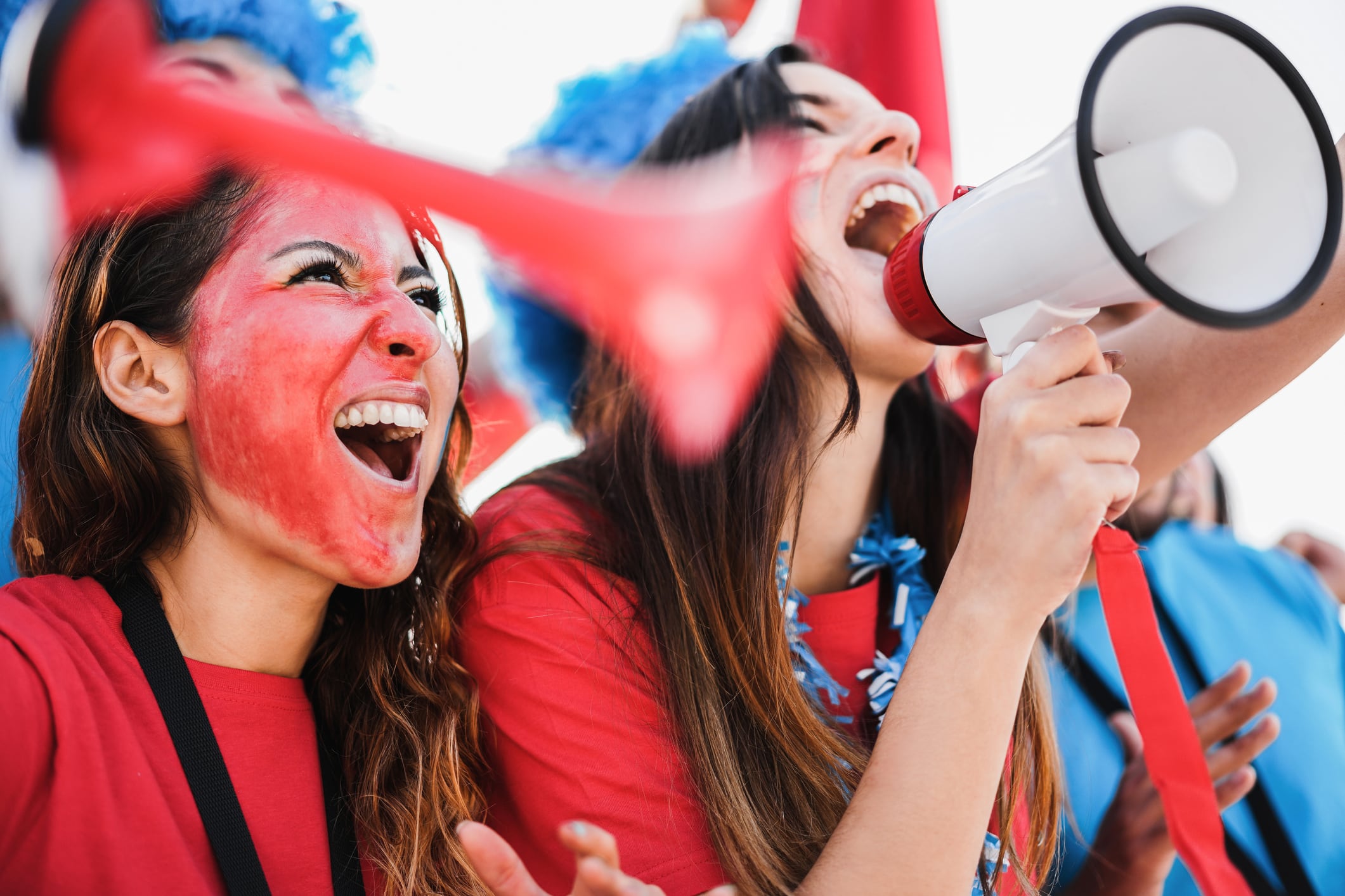 Mujeres gritando, alguna con un megáfono, en un encuentro deportivo