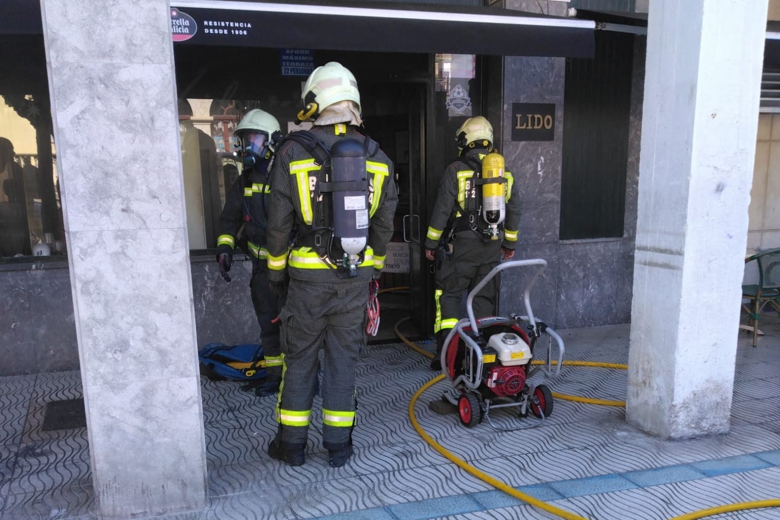 Bomberos a las puertas de la cafetería incendiada en Laredo.