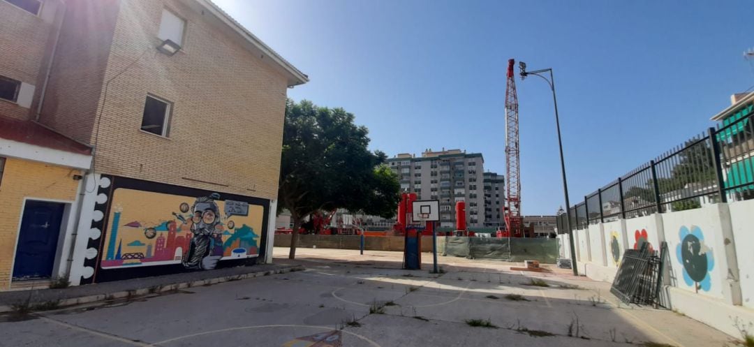 Patio del Colegio Valle-Inclán en la barriada de Echeverría, en El Palo. Las grúas de las obras del aparcamiento al fondo