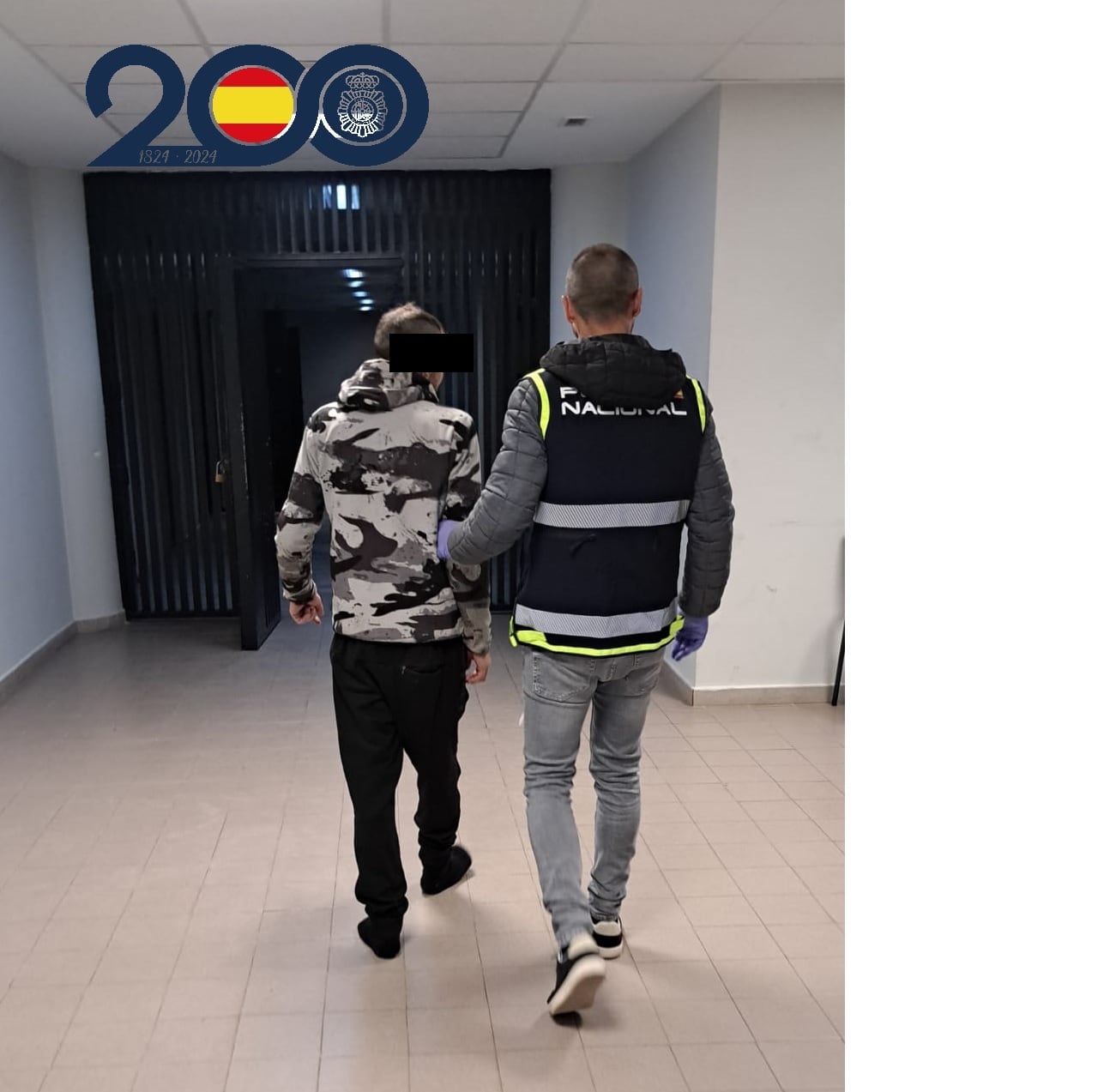 Un agente de Policía Nacional custodia a uno de los detenidos