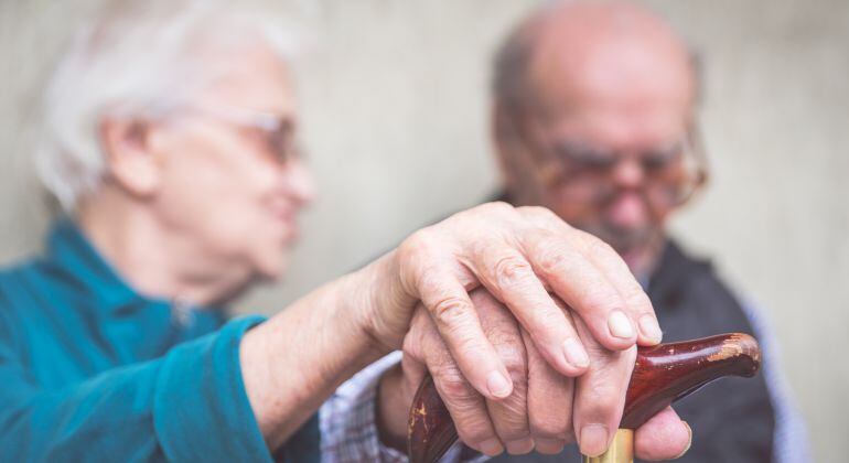 Imagen de una pareja de personas mayores cogiéndose de la mano. 