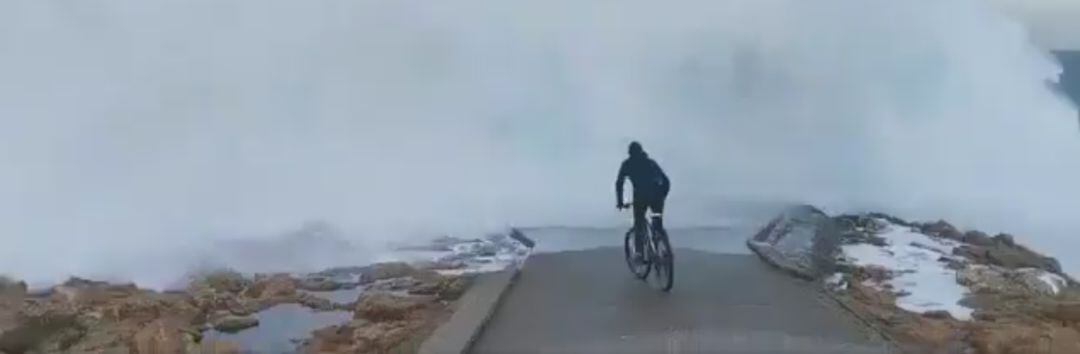 Ciclista acercándose al oleaje en A Coruña