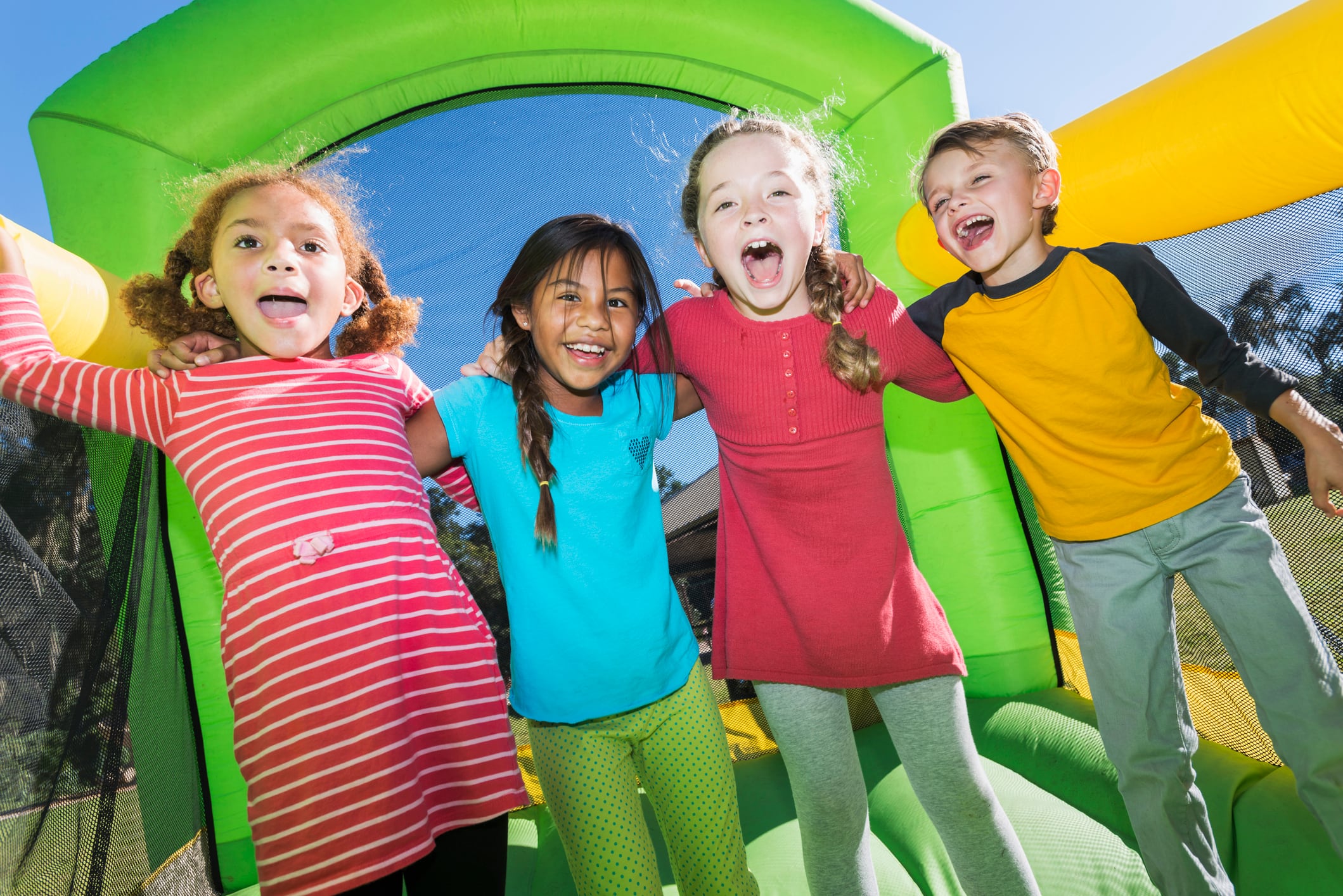 Un grupo de niños y niñas jugando en un castillo hinchable.