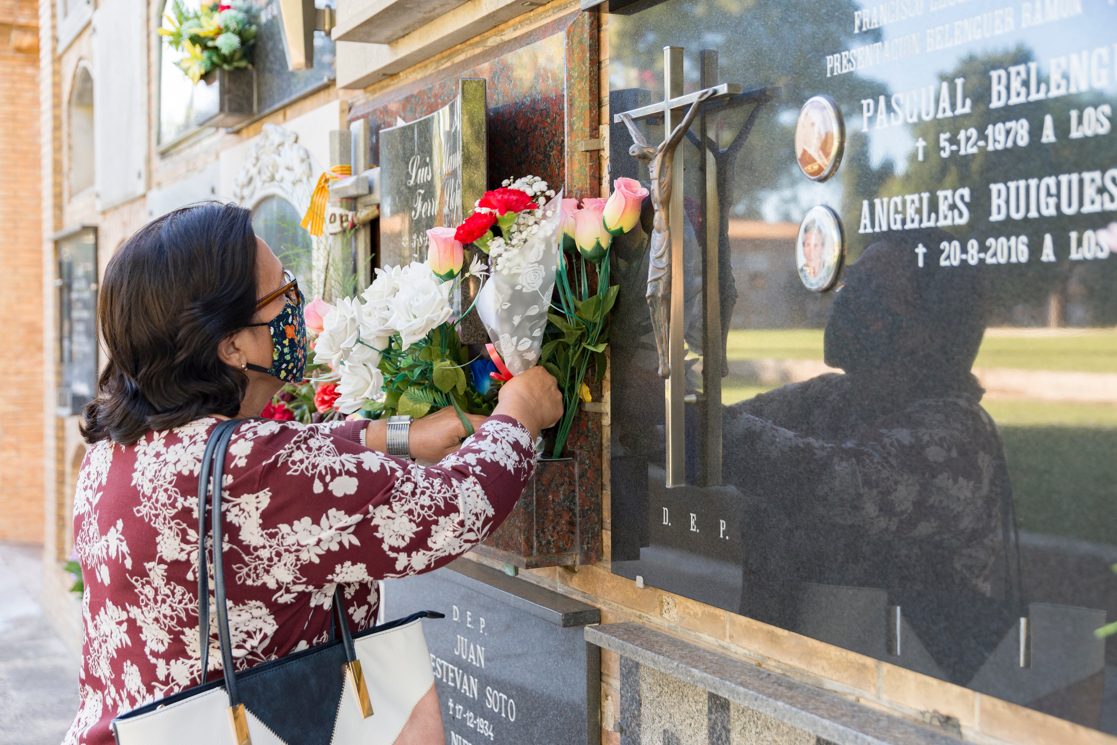 Imagen de archivo de una mujer depositando flores en un cementerio de València