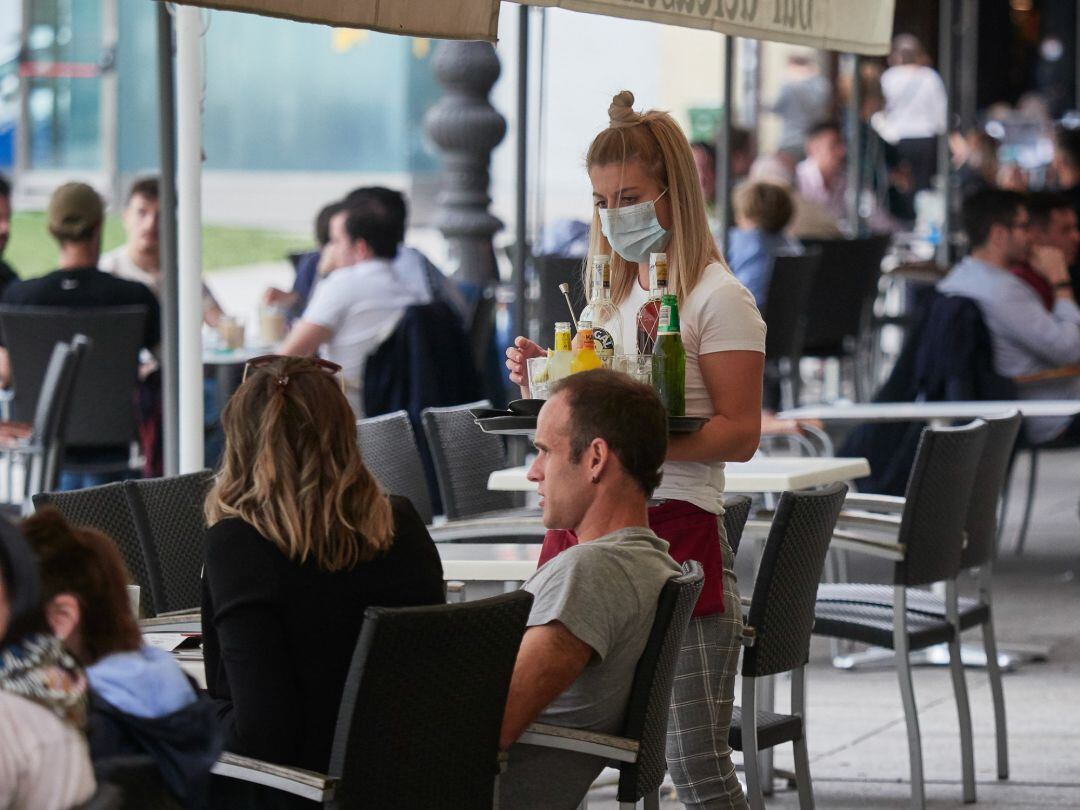Una trabajadora atiende a los clientes de una terraza.