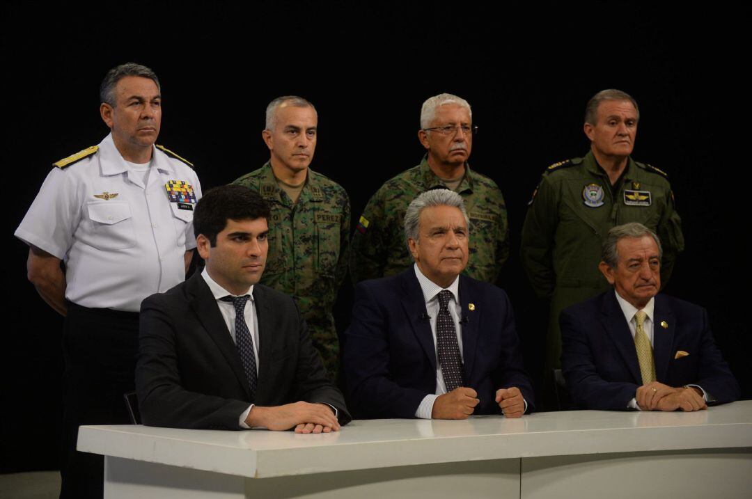 Fotografía cedida que muestra al presidente ecuatoriano, Lenín Moreno (c sentado), quien se dirige acompañado por el vicepresidente, Otto Sonneholzner (i); y el ministro de Defensa, Oswaldo Jarrín (d), este lunes a la nación en un mensaje por cadena nacional en Guayaquil. 