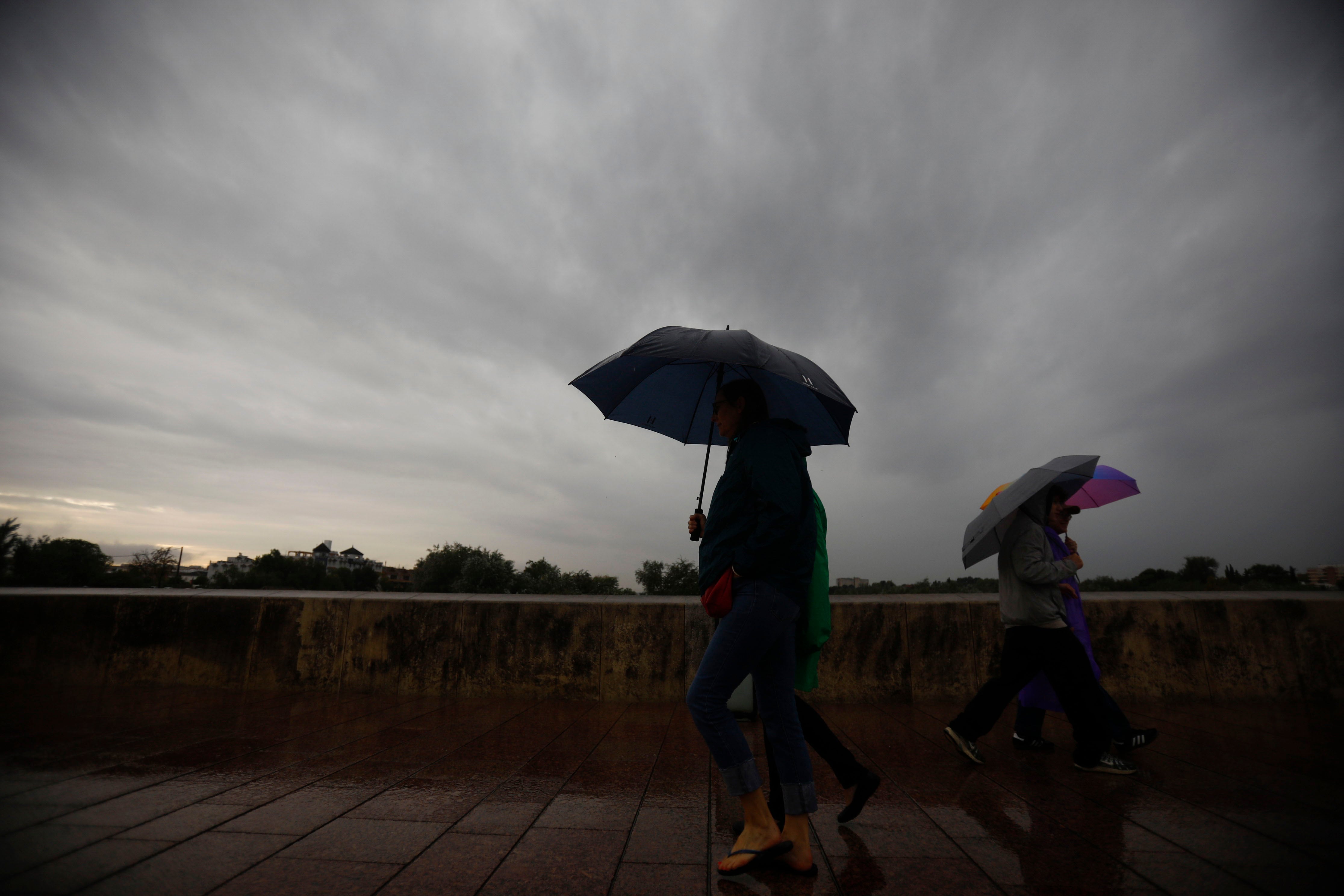 FOTODELDIA CÓRDOBA (ESPAÑA), 14/11/2025.- Unas personas tratan de protegerse de la lluvia y de las rachas de viento este viernes en Córdoba por el paso de la borrasca Claudia. EFE/Salas