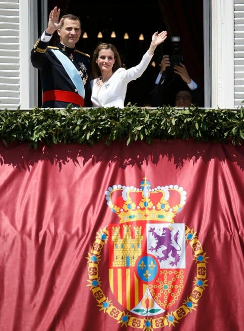 Los reyes de España saludan desde el balcón del Palacio Real.