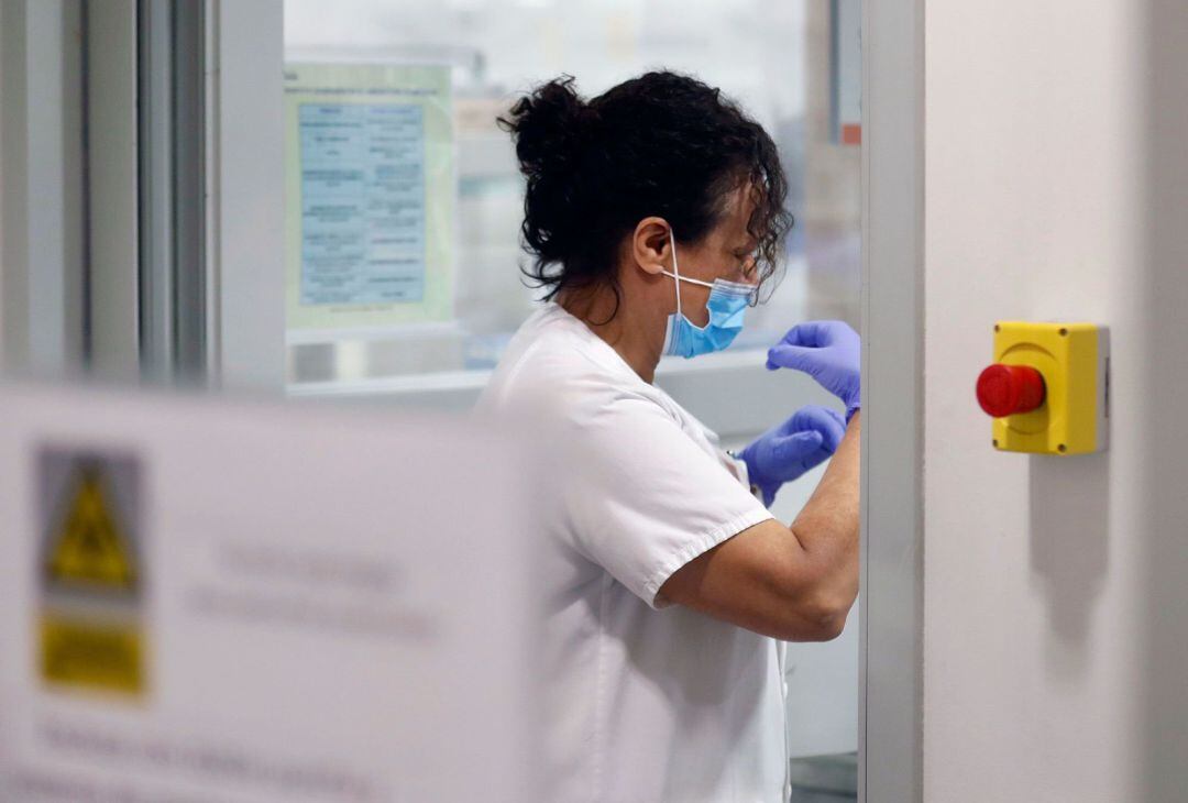 Técnicos sanitarios trabajan en el interior de la cabina de seguridad del laboratorio de virología. EFE J.L. Cereijido