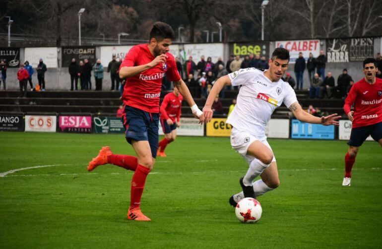 Pol Bueso defiende el balón ante y jugador del Olot