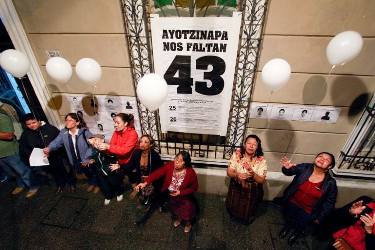 People hold white balloons while standing next to a poster that reads, &quot;We are missing 43&quot;, during an event to mark the first anniversary of the disappearance of the students from Mexico&#039;s Ayotzinapa College Raul Isidro Burgos, in Guatemala City, Septembe