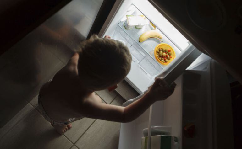 Un niño abre un frigorífico casi vacío
