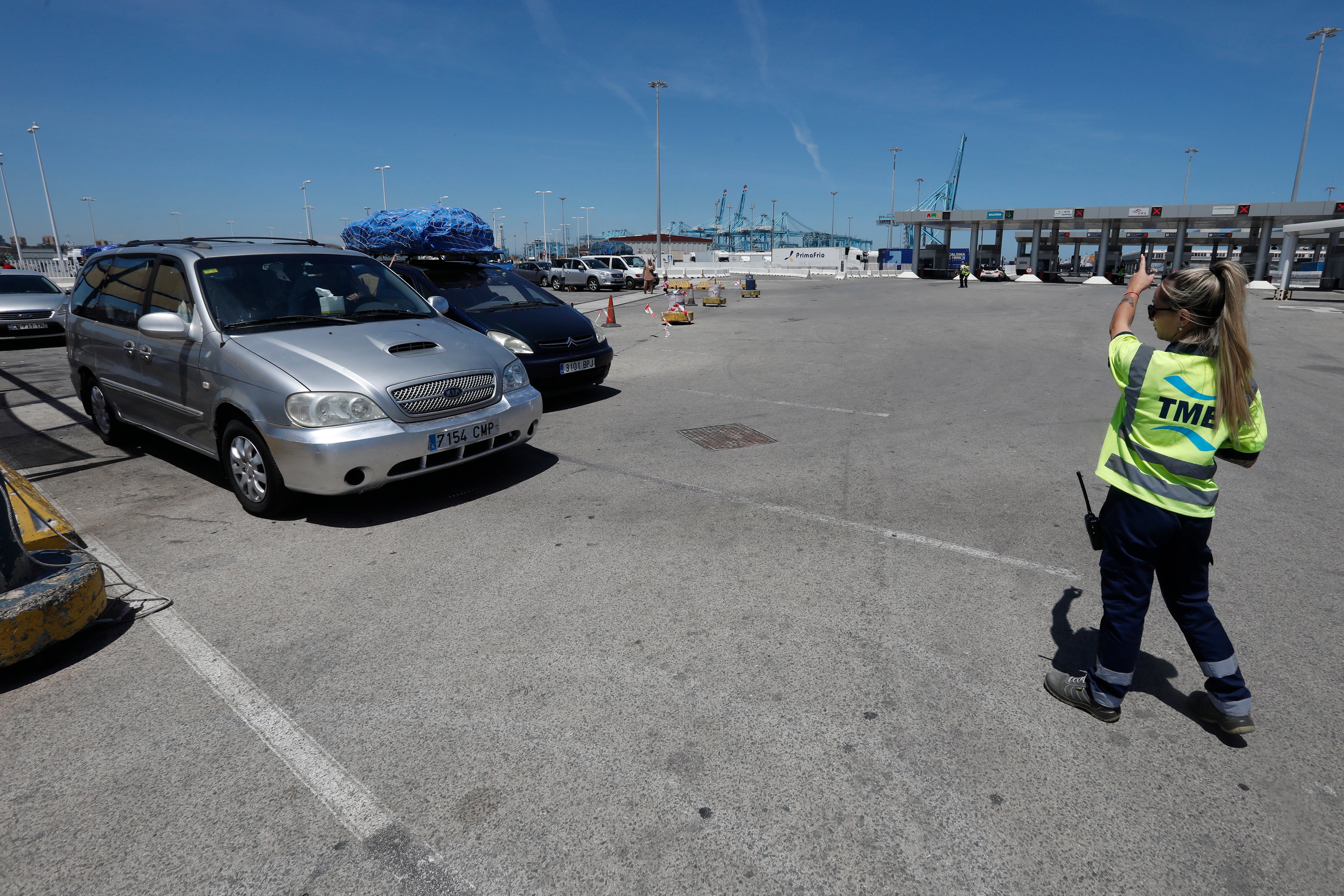 GRAFAND2813. ALGECIRAS (CÁDIZ), 15/06/2023.-Una operaria del puerto de Algeciras indica a los vehículos la zona de embarque del puerto gaditano, este jueves cuando se ha activado el dispositivo de la Operación Paso del Estrecho (OPE). EFE/A.Carrasco Ragel.
