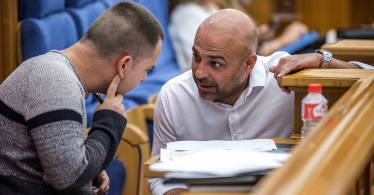 El secretario general de Podemos en Castilla-La Mancha, José García Molina (d), conversa con el portavoz del grupo parlamentario, David Llorente, durante la segunda y última jornada del Debate sobre el Estado de la Región