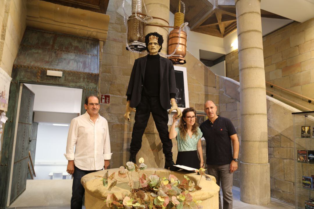 Kote Guevara, bibliotecario, Leire Cano de Ereite Kultur Zerbitzuak y Juan Luis Silanes, concejal de Cultura, junto a la figura de Frankenstein protagonista de la exposición. 