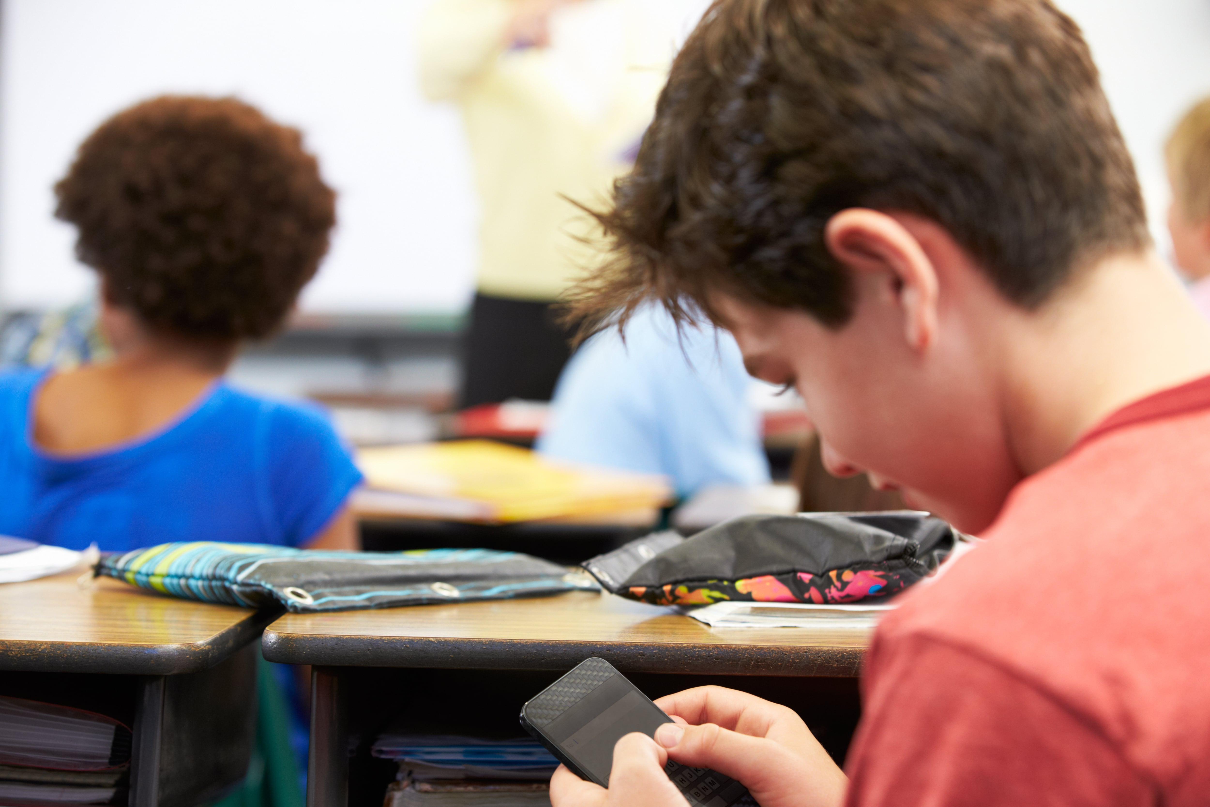 Alumno usando el teléfono móvil en clase