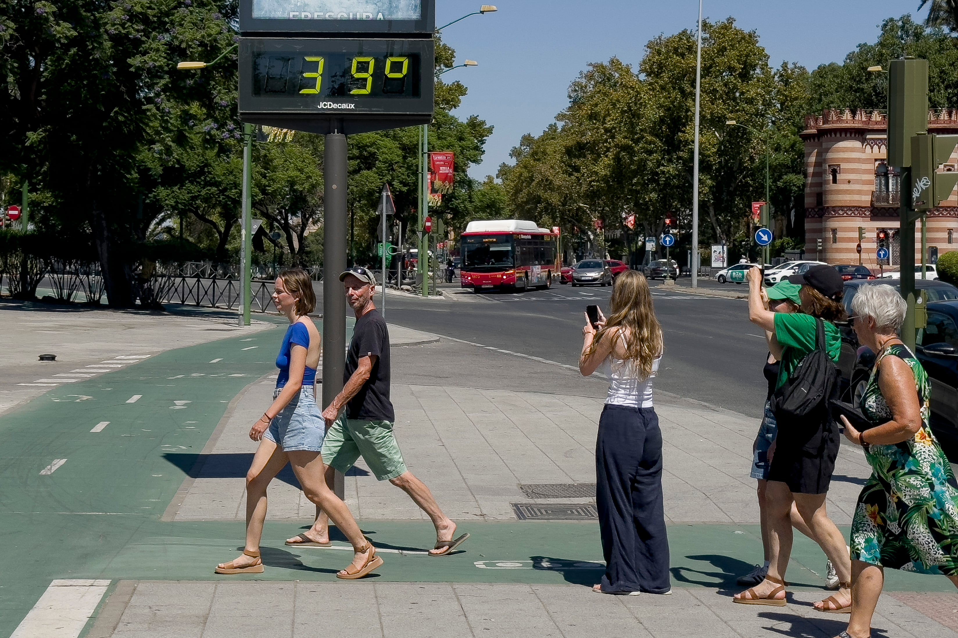 Un grupo de personas pasea por una calle de Sevilla donde la Agencia Estatal de Meteorología (Aemet) ha declarado la alerta naranja por altas temperaturas. EFE/David Arjona