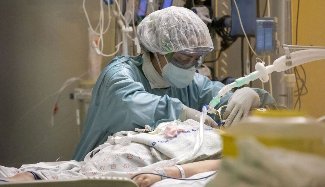 Una profesional sanitaria atiende a un enfermo en una UCI.