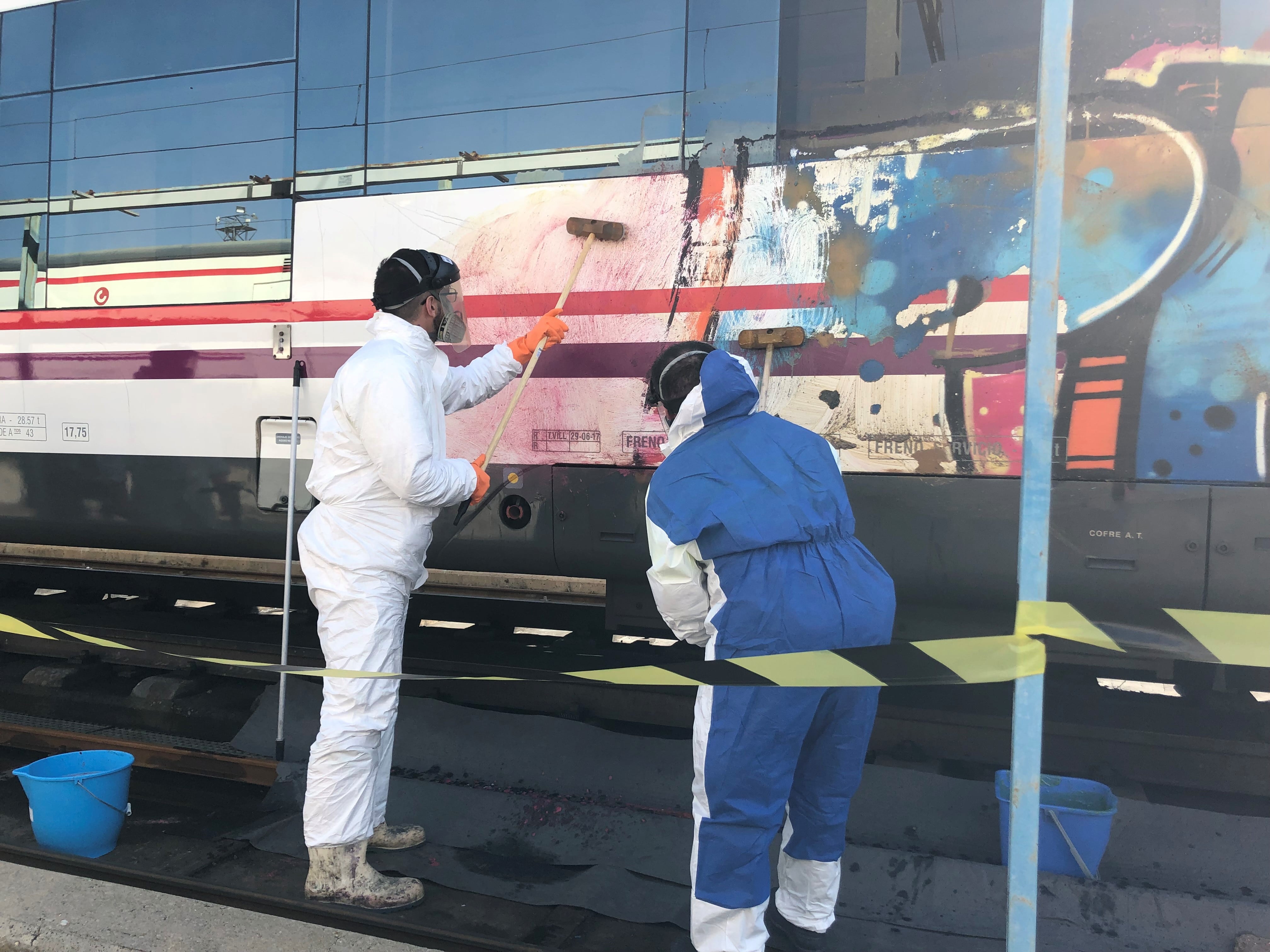 Operarios limpiando los graffitis de los trenes de Renfe.