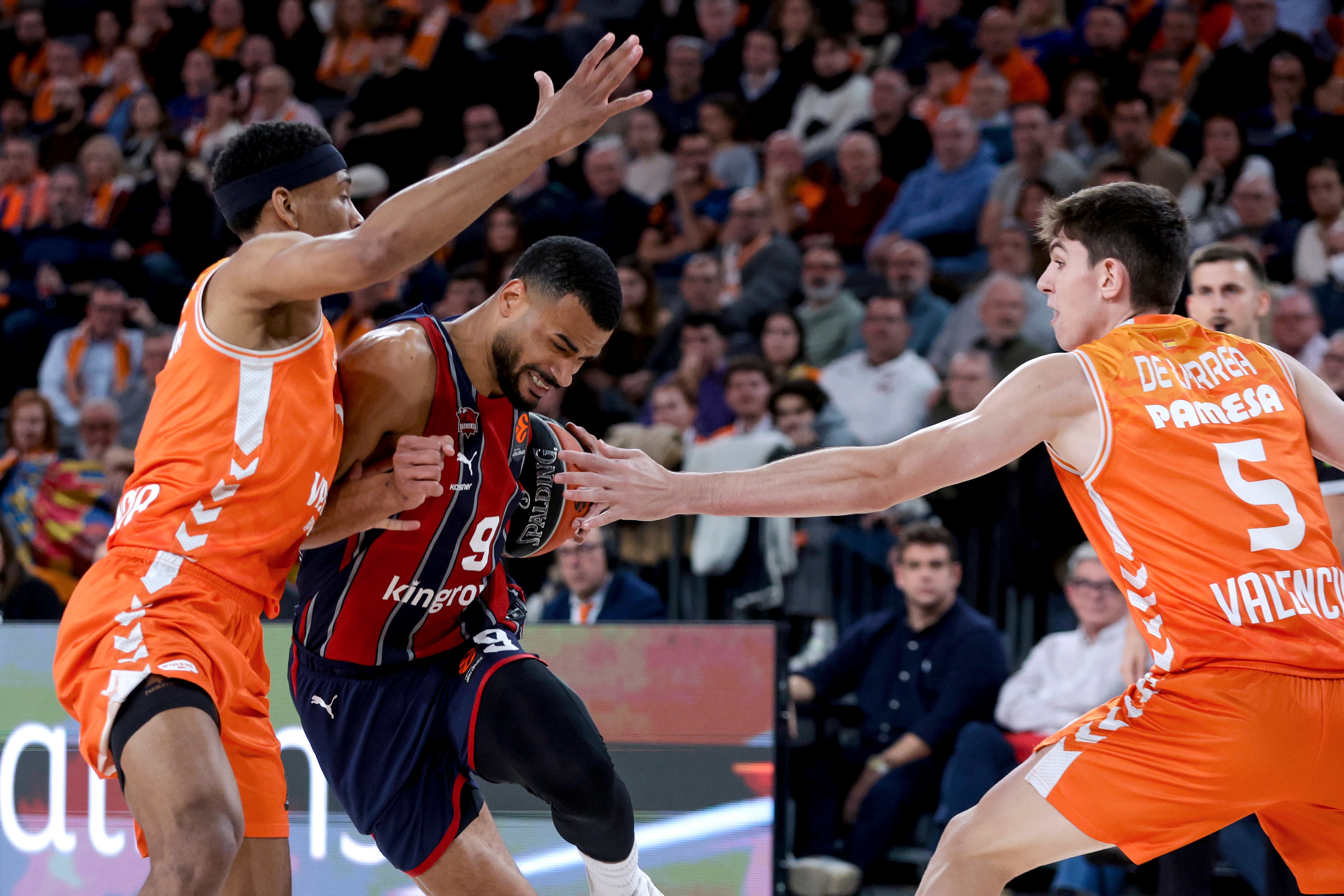 VALENCIA, 23/12/2025.- El jugador del Baskonia Timothe Luwawu-Cabarrot (c) juega un balón ante Kameron Taylor (i), del Valencia Basket, durante el partido de baloncesto correspondiente a la jornada 18 de la Euroliga entre el Baskonia y el Valencia Basket en el Roig Arena de Valencia, este martes. EFE/ Miguel Ángel Polo