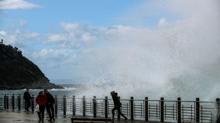 Una mujer es sorprendida por una ola en el Paseo Nuevo de San Sebastián.