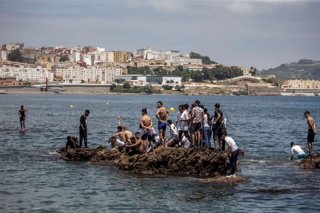  Un grupo de inmigrantes sobre una roca rodeada de agua en la playa fronteriza de El Tarajal de Ceuta, este martes en una avalancha de inmigrantes sin precedentes en España al registrarse la entrada en 24 horas de 5.000 personas (un tercio de ellas menores).