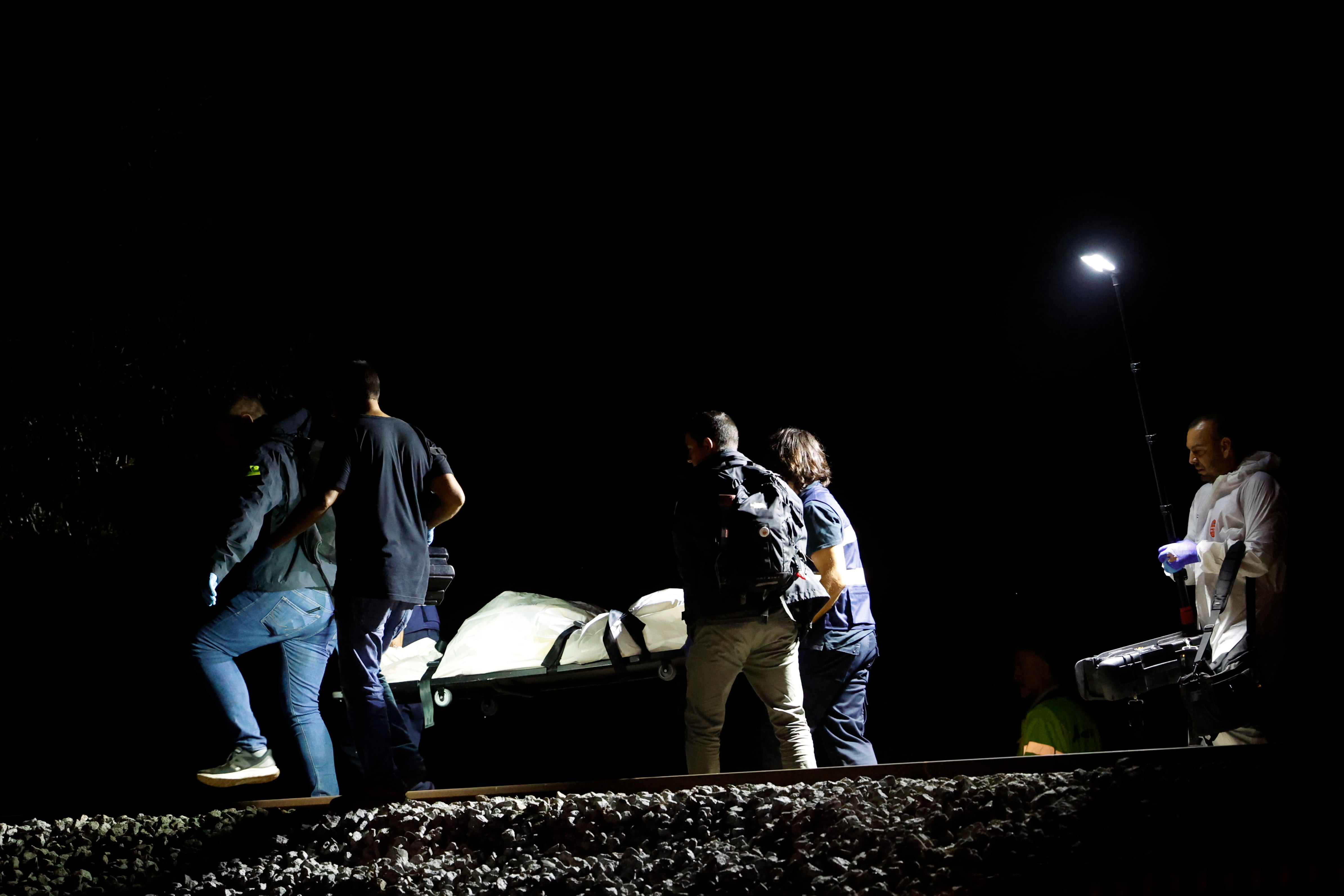 Los operarios retiran el último cadáver después de que cuatro personas fallecieran este domingo por la noche al ser arrolladas por un tren a la altura de Montmeló, en la comarca del Vallès Oriental (Barcelona), cuando un grupo de siete personas trataba de cruzar la vía por un punto no autorizado.