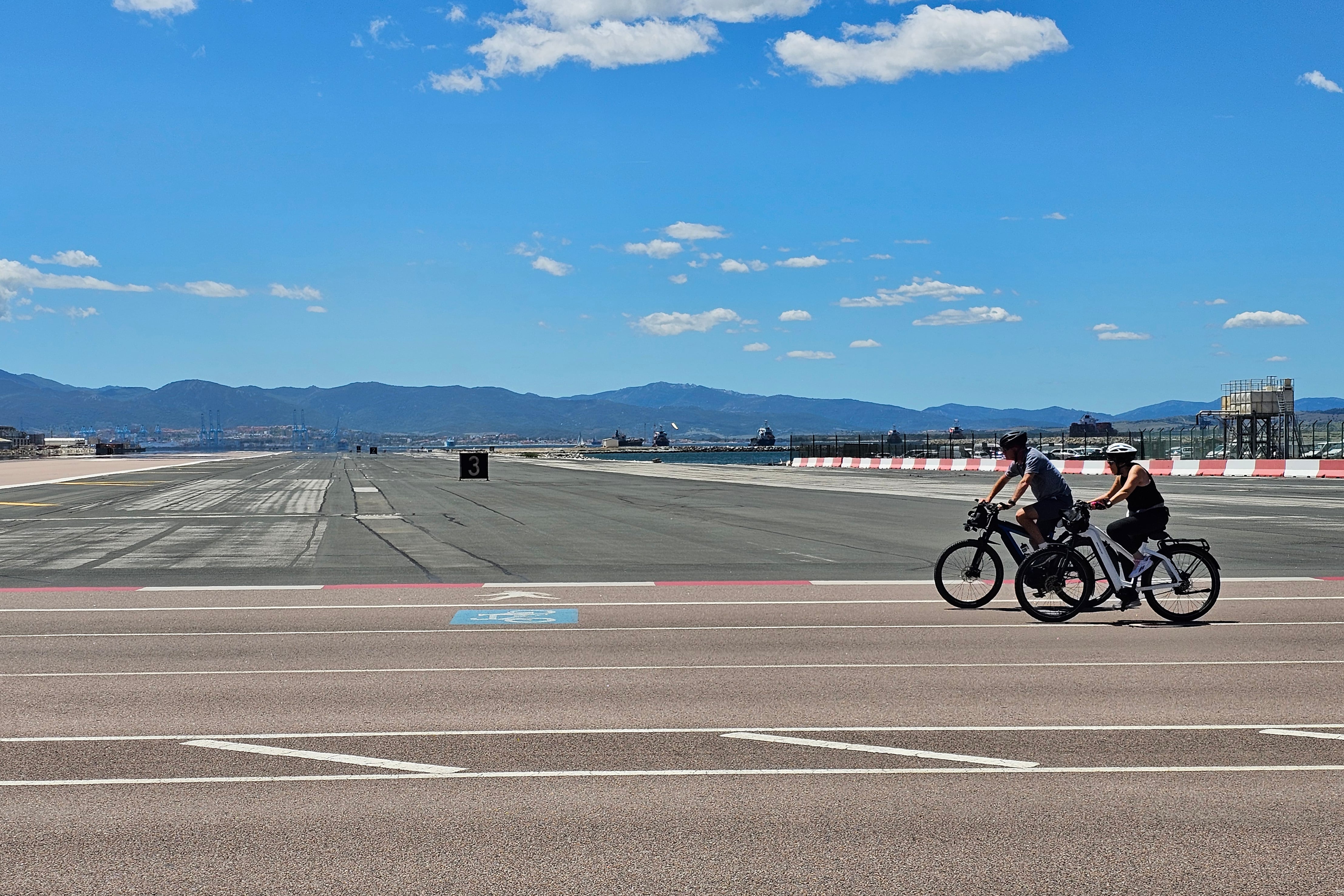 GRAFAND1275. GIBRALTAR, 16/05/2024.- Dos ciclistas cruzan el aeropuerto de Gibraltar, este jueves cuando los ministros de Asuntos Exteriores de España y Reino Unido, José Manuel Albares y David Cameron, se reúnen en Bruselas con el vicepresidente ejecutivo de la Comisión Europea, Maro efcovic, y el ministro principal de Gibraltar, Fabián Picardo, para avanzar en un acuerdo sobre el Peñón tras el Brexit. EFE/A.Carrasco Ragel.
