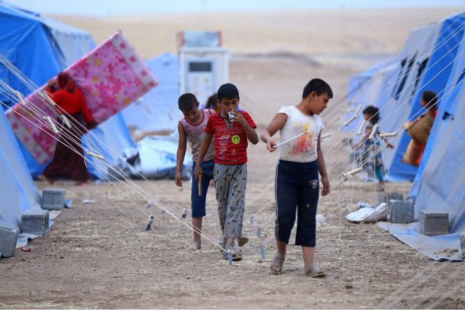 Un grupo de niños iraquíes caminan por un campamento de refugiados cerca a la ciudad de Erbil (Irak)