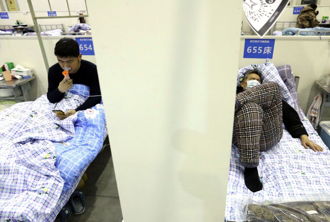 Pacientes descansan en sus camas dentro del Centro de Convenciones Wuhan Parlor que se ha convertido en un hospital improvisado tras un brote del nuevo coronavirus