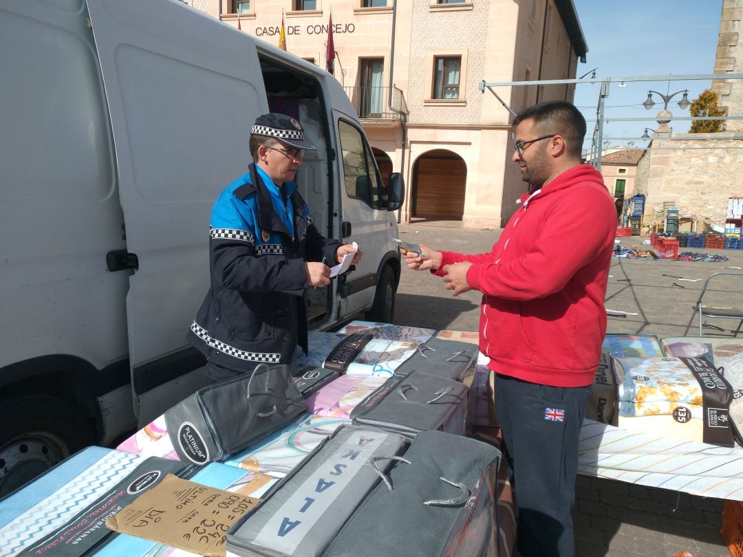 Un vigilante municipal de Cantalejo cobra la tasa a uno de los comerciantes en el mercado semana. Imagen de archivo