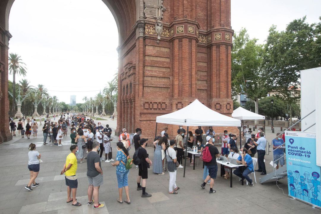 Numerosas personas esperan para vacunarse en un punto móvil instalado en Arco de Triunfo, en Barcelona.