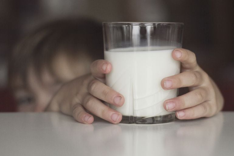 Un niño, dispuesto a tomarse un vaso de leche.