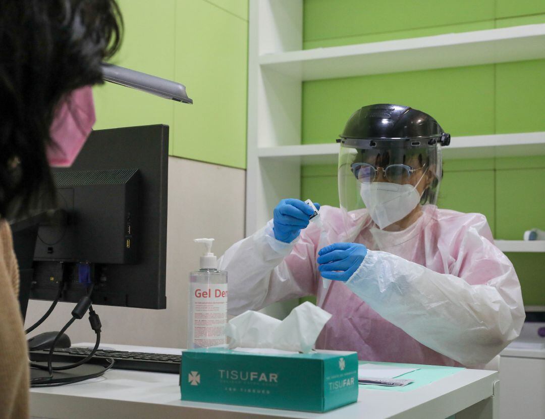 Una trabajadora sanitaria atiende a una mujer antes de realizarse un test de antígenos en una farmacia