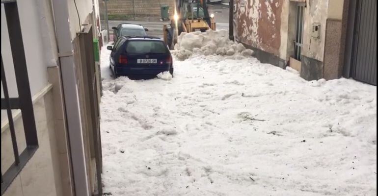 Una grúa municipal intenta retirar las montañas de granizo de una calle de Castillo de Locubín.