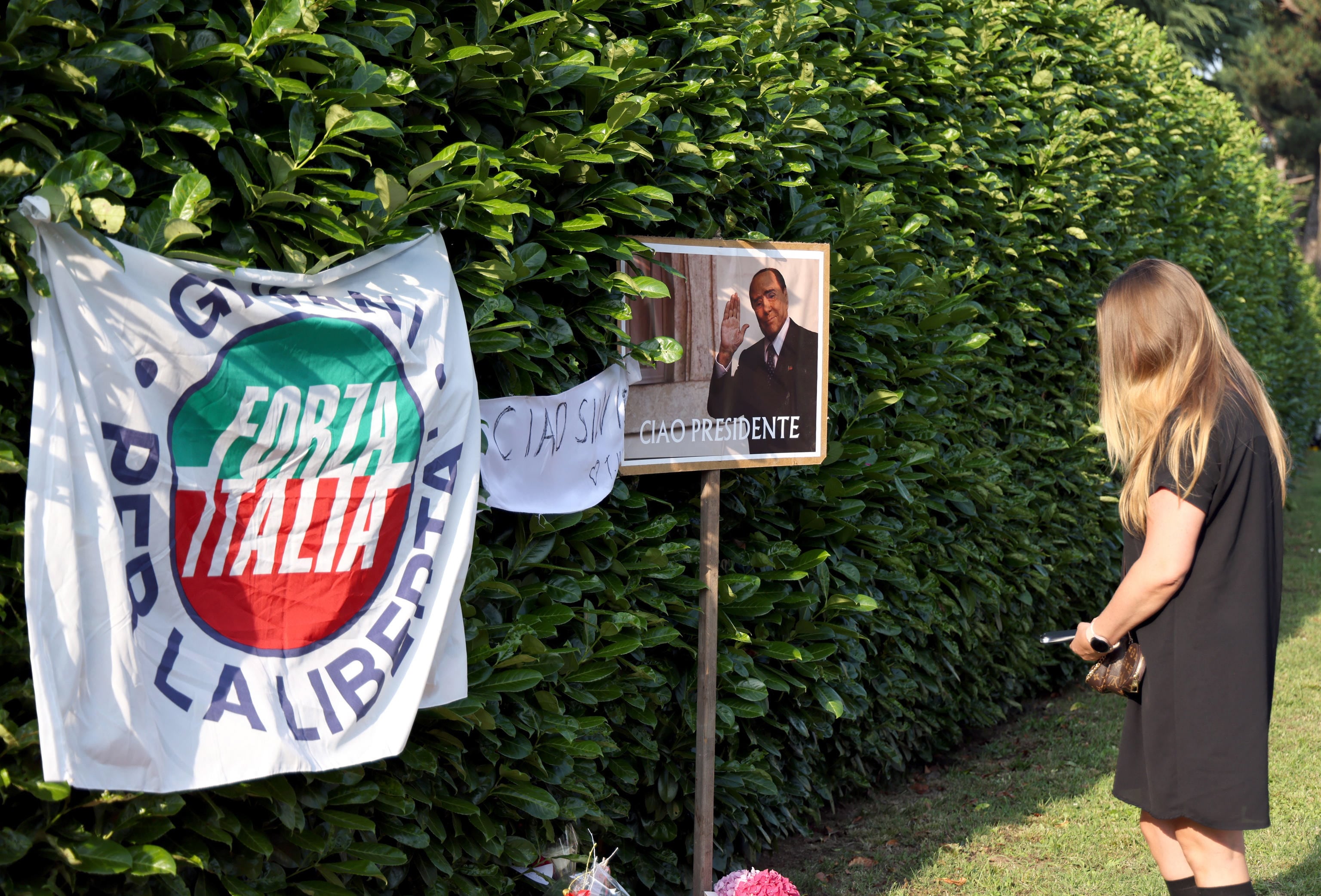 Una mujer deja un ramo de flores a la entrada de la residencia de Villa San Martino en Arcore tras el fallecimiento del ex primer ministro italiano Silvio Berlusconi.