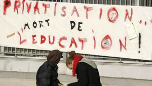 Dos estudiantes francesas, junto a una pancarta donde se lee: "Privatización: muerte de la educación"
