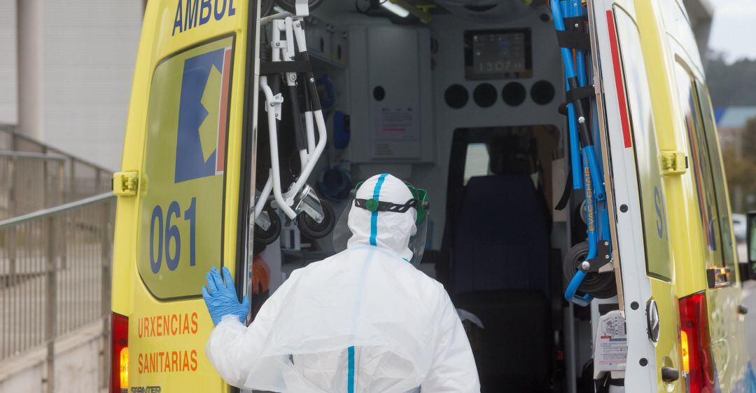 Un trabajador sanitario totalmente protegido cierra la puerta de una ambulancia