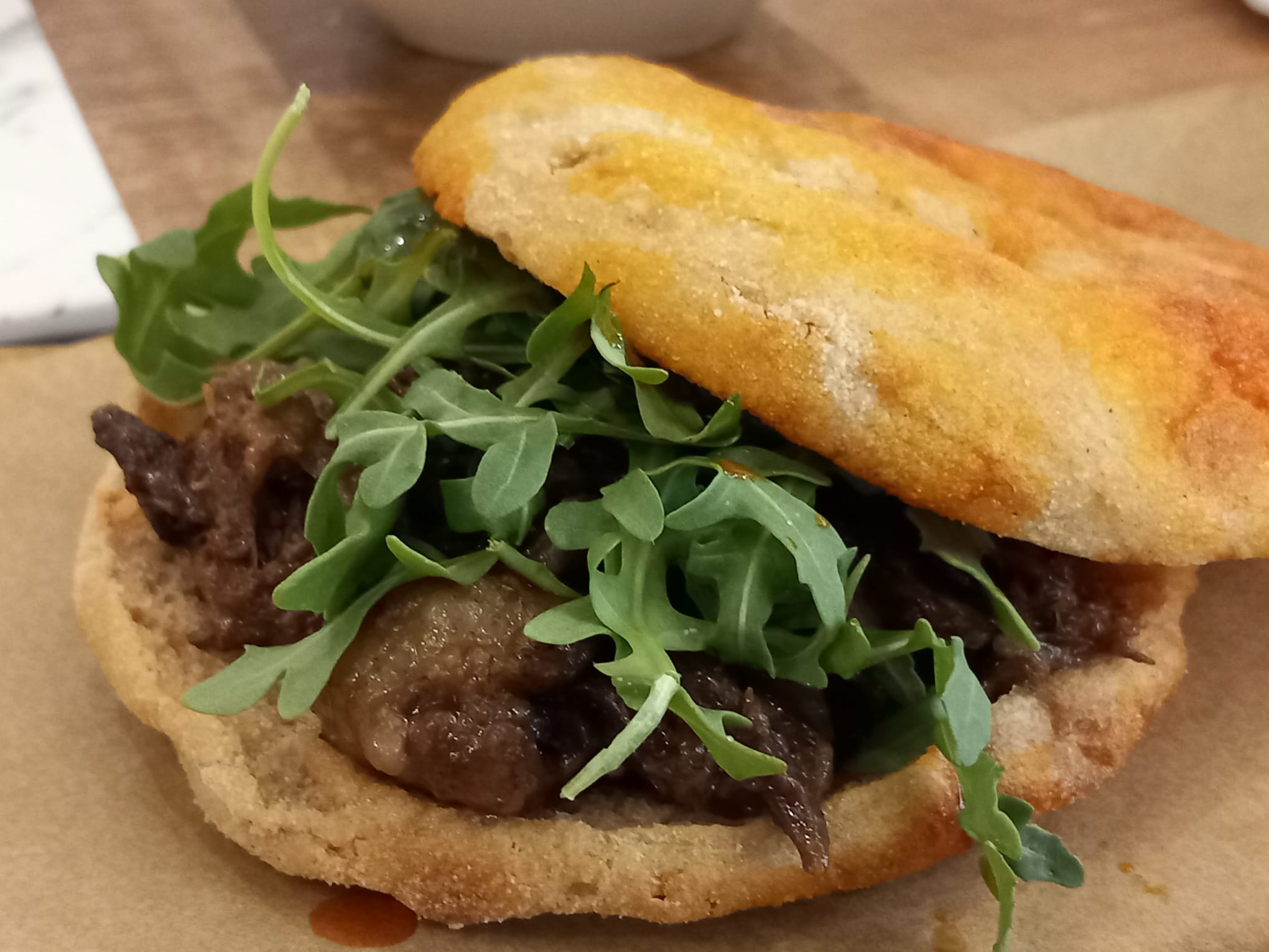 Focaccia cristal rellena de rabo de toro, rúcula y holandesa de manteca colorá