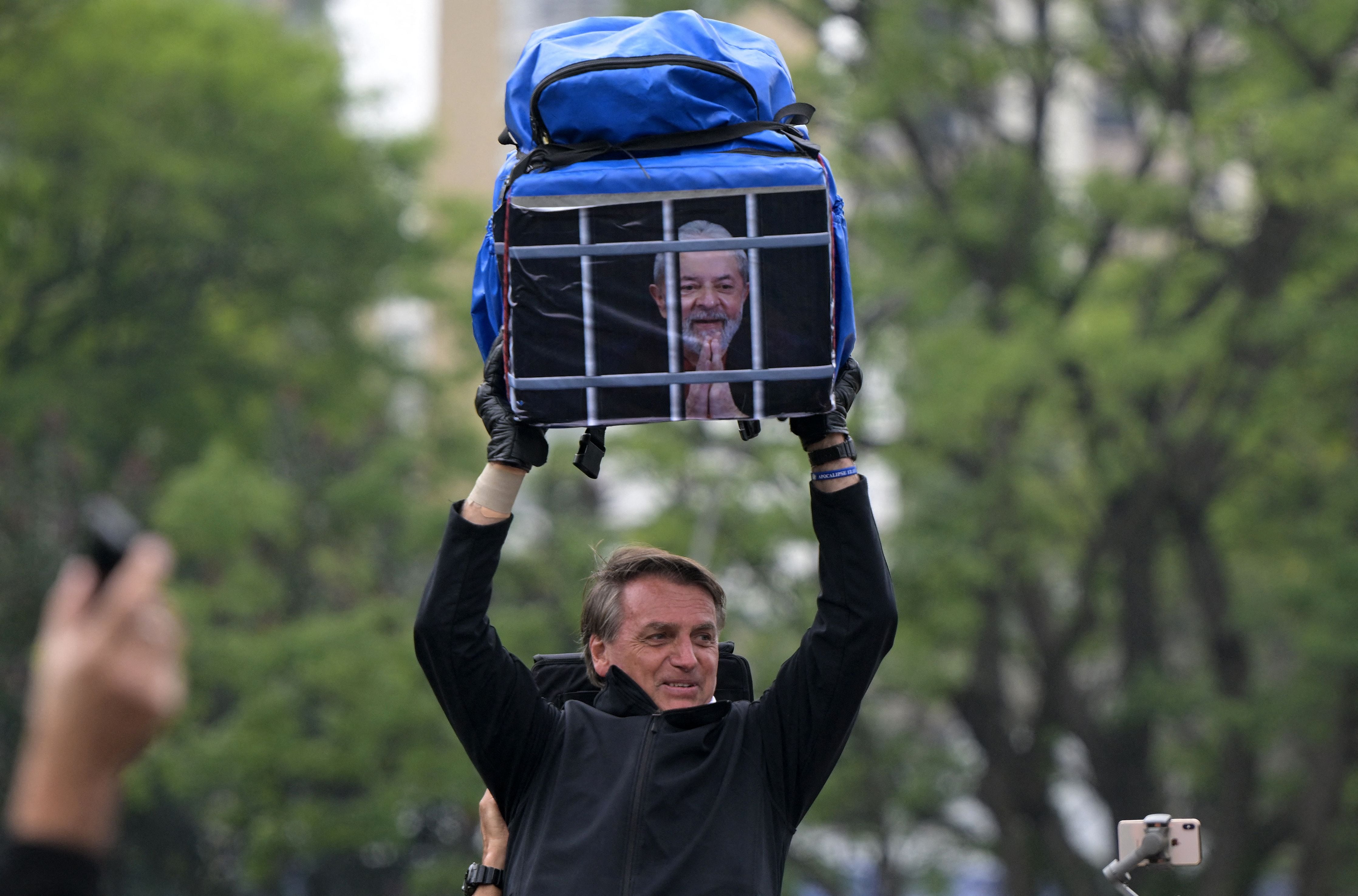 El presidente de Brasil, Jair Bolsonaro, paseándose ayer por las calles con una bolsa en la que se ve a Lula da Silva en prisión