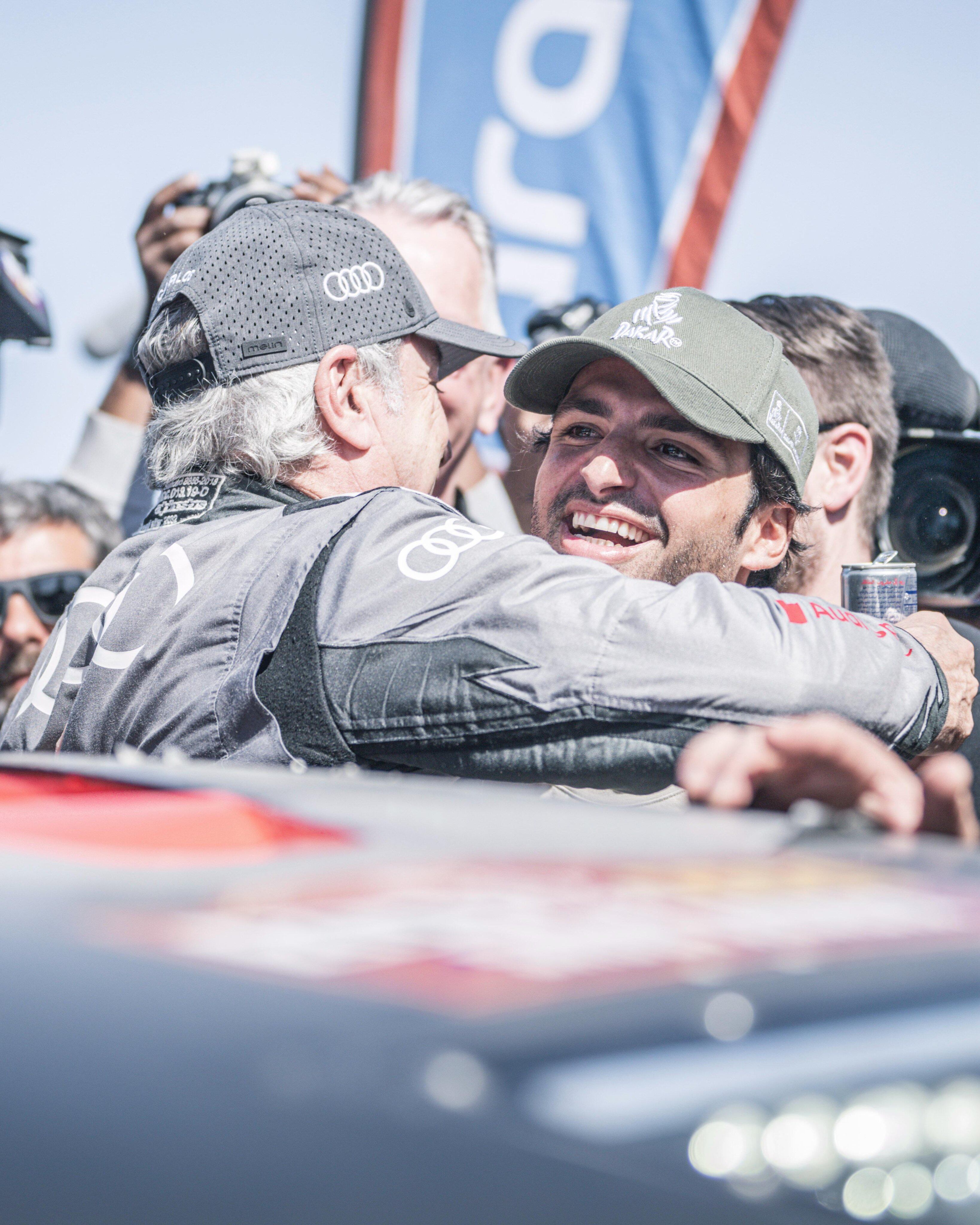 Carlos Sainz se abraza con Sainz Jr después de conseguir su cuarto Dakar