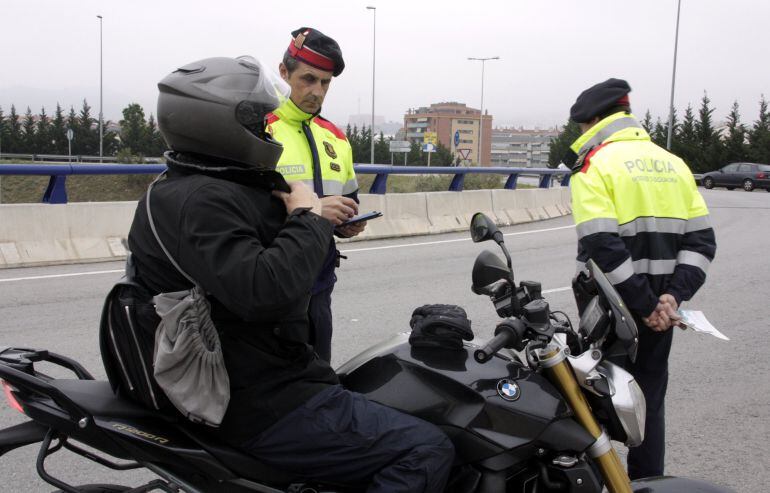 Imatge d'un agent demanant la documentació a un motorista en el control realitzat pels Mossos d'Esquadra en una rotonda de l'A2 a Cornellà de Llobregat. (Horitzontal)