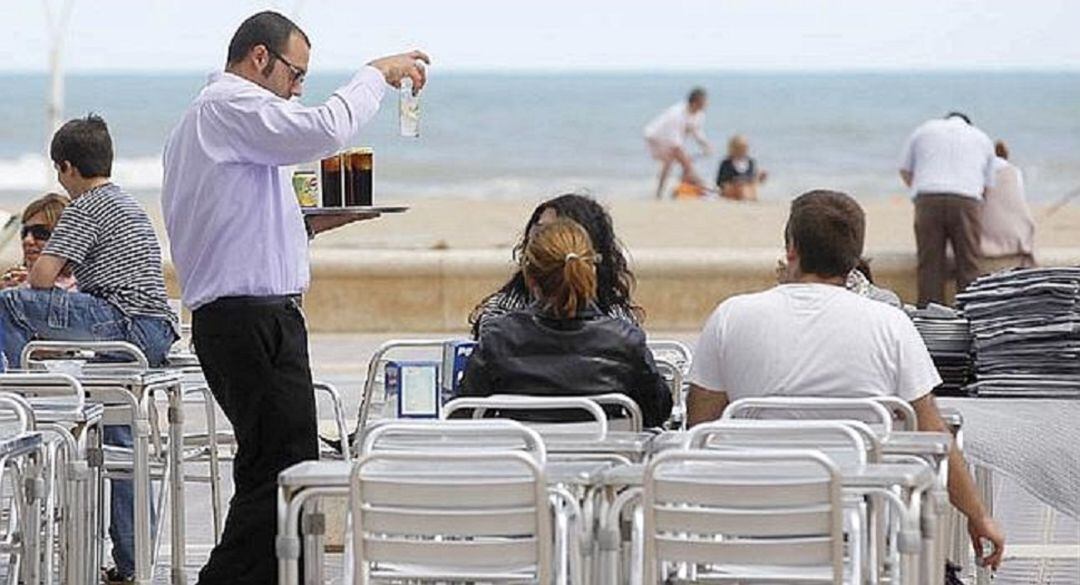 Un camarero atendiendo a unos clientes en una terraza.