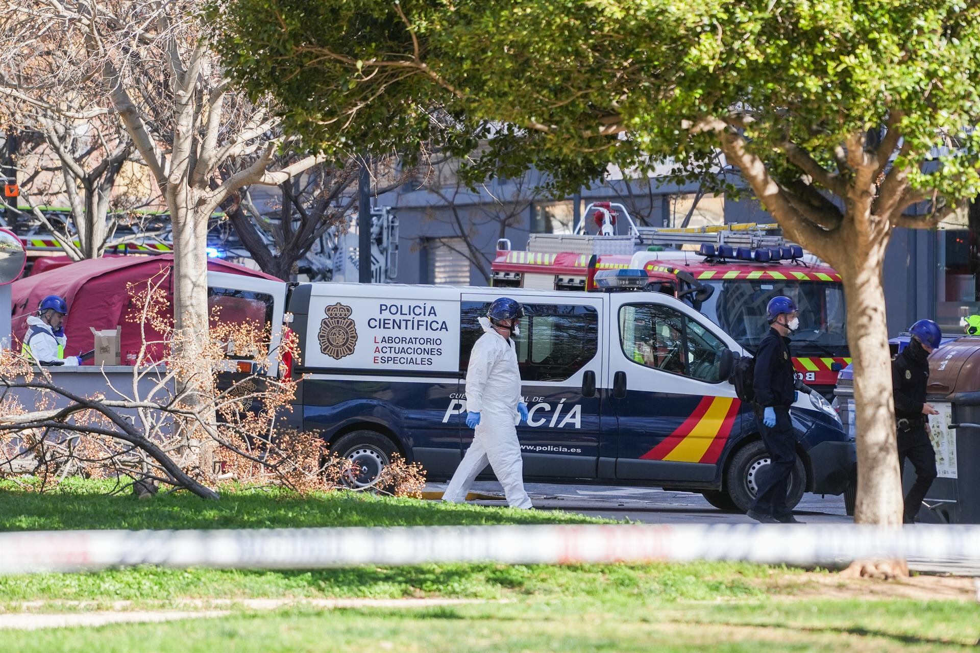 Un vehículo y agentes de la Policía Científica se dirigen a entrar en el edificio tras el incendio en el barrio de Campanar