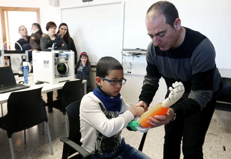 Los científicos están mejorando la integración de las prótesis de brazos en pacientes amputados. En la foto, el profesor del CIFP Don Bosco de Errenteria, Carlos Lizarbe hace entrega de un brazo artificial diseñado con impresora 3 D a un niño. 