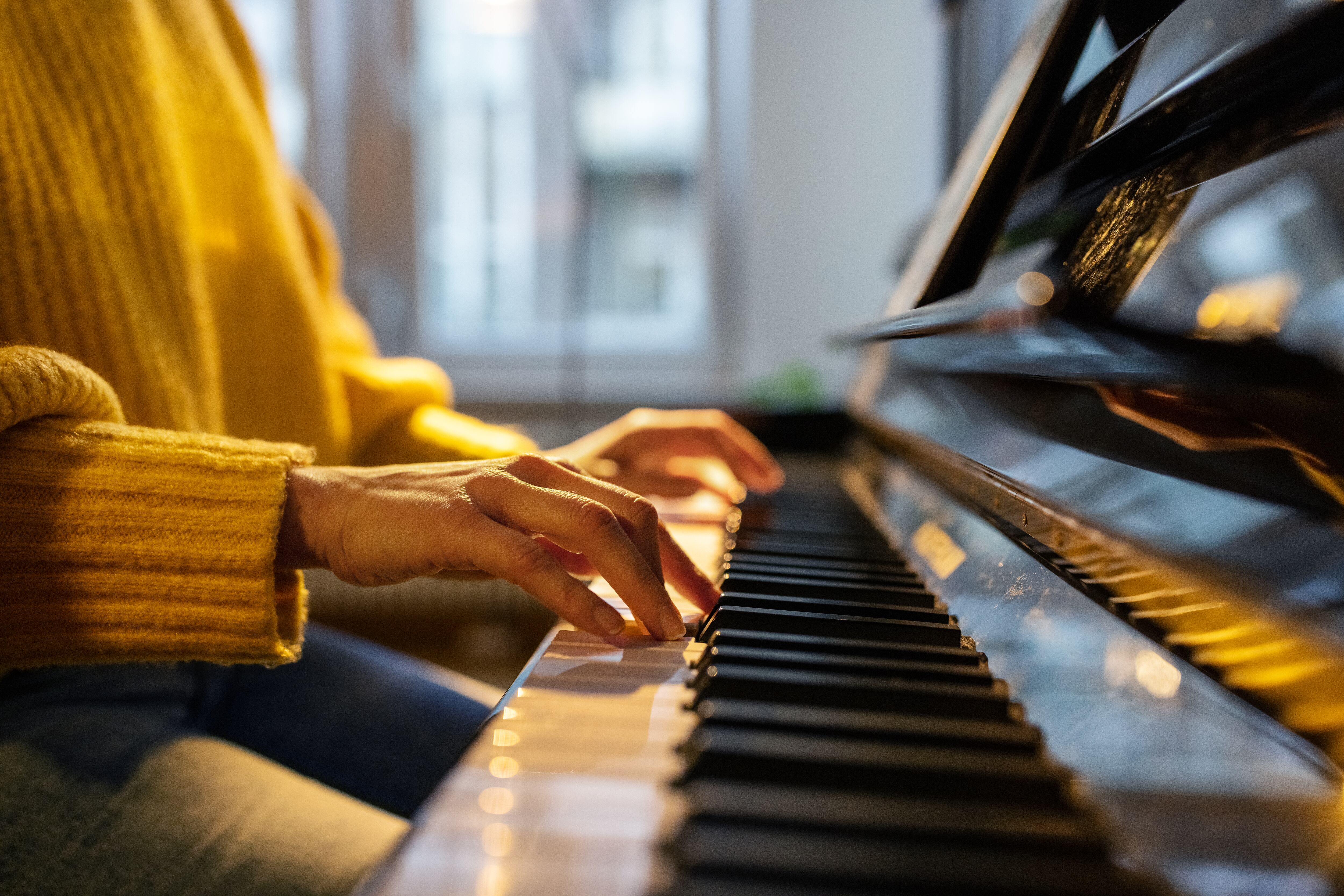 Close-up of female hands playing piano. Woman learning to play piano at home.