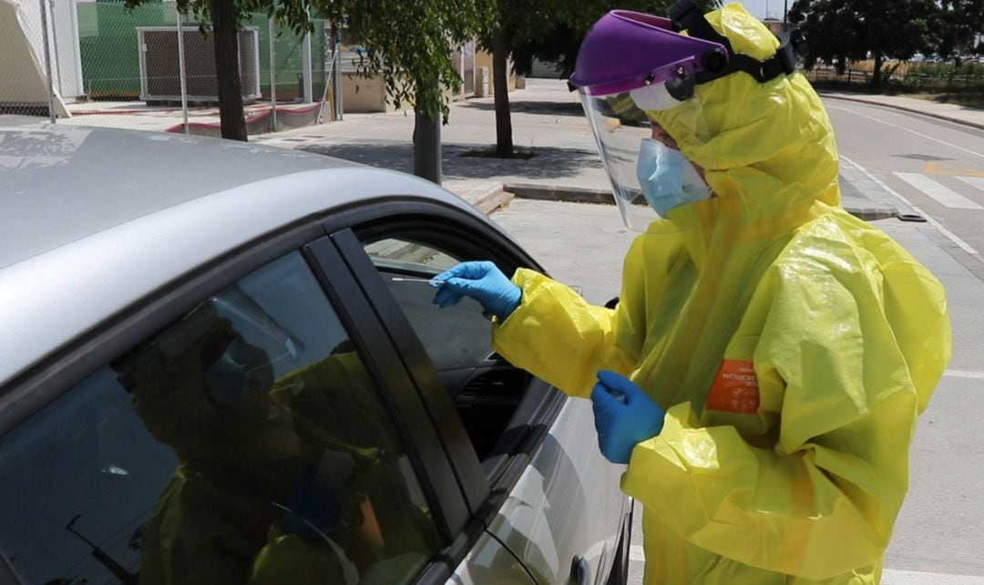 Una sanitaria realiza una prueba PCR a una persona que está en un coche.
