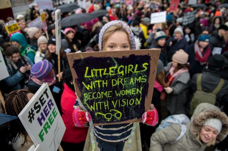 Una niña muestra un cartel con la leyenda &quot;las niñas con sueños se convierten en mujeres con visión&quot;. 